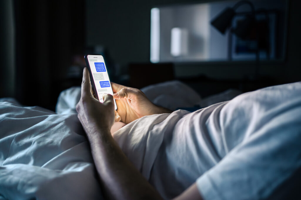 Mann mit Smartphone im Bett