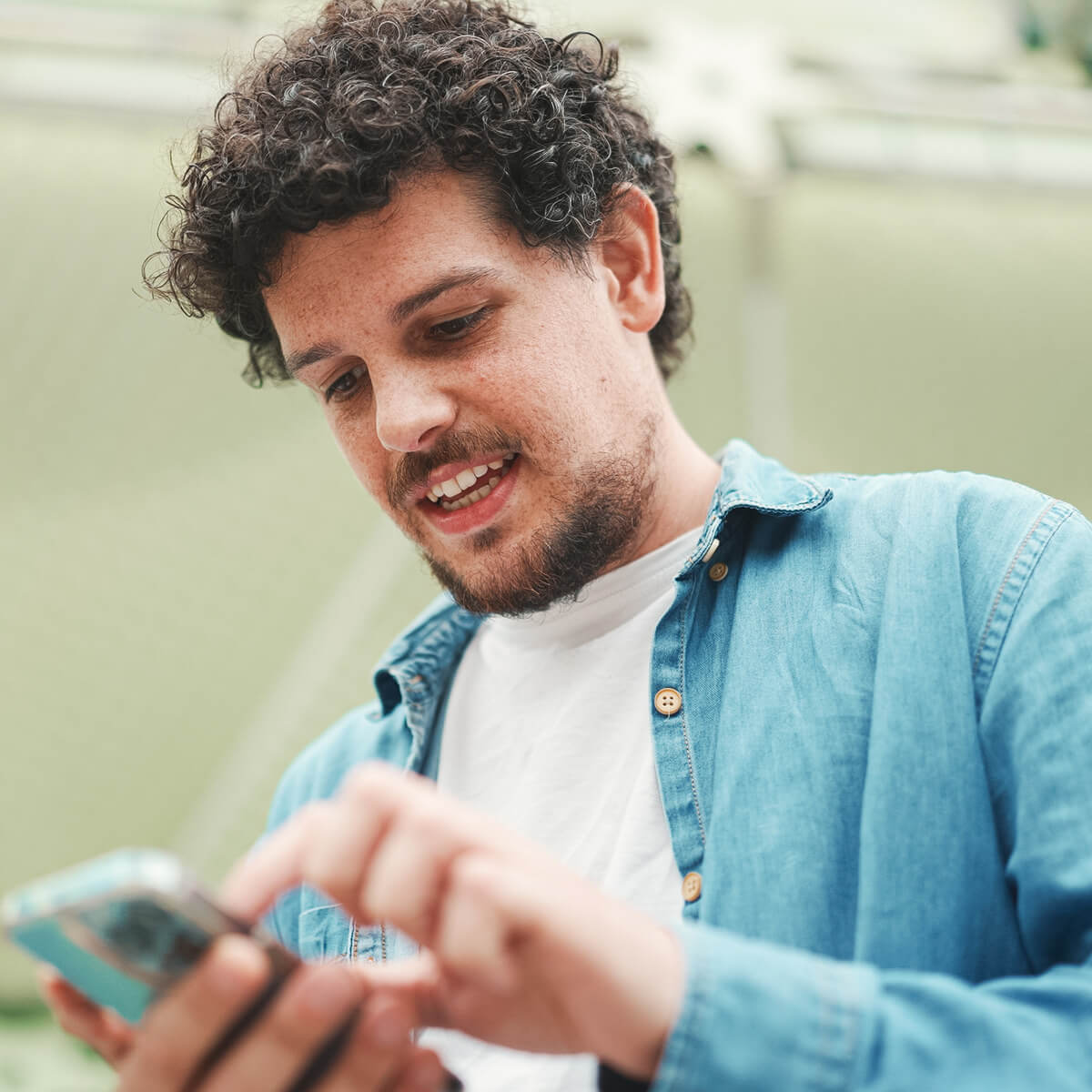 Junger Mann blickt unterwegs auf seinem Smartphone in die somnio App