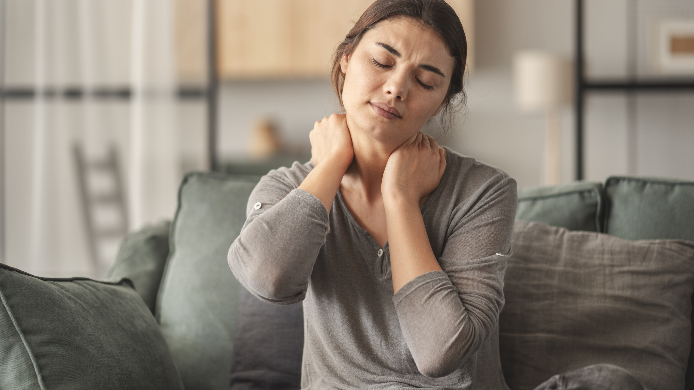 Frau mit chronischen Schmerzen fässt sich an den Nacken